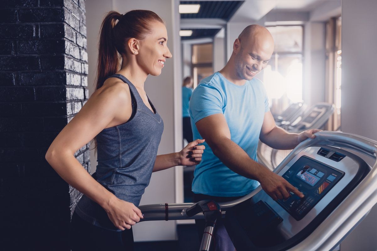 Personal training with a trainer on a treadmill. The trainer controls the correctness of the exercise when using a treadmill for cardio. Control coach in the gym. Athletic jogging with a trainer